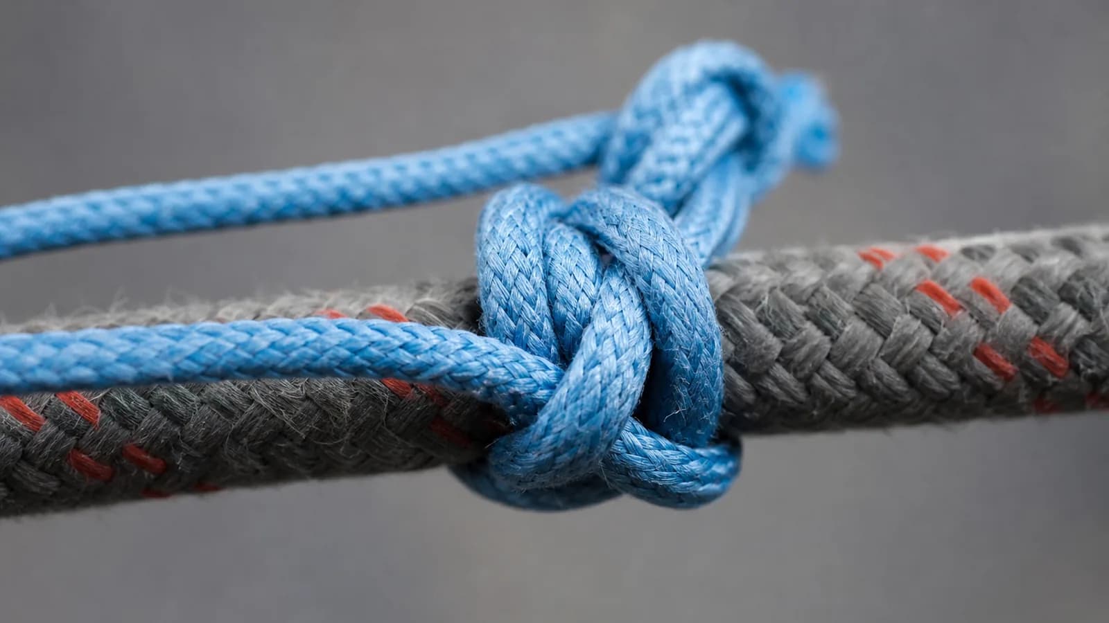 Comparatif visuel d'un Machard tubulaire en spirale et d'un prussik en tours symétriques sur deux brins de corde dynamique parallèles, cordelettes orange et bleue Ø 7 mm en boucle, gros plan technique