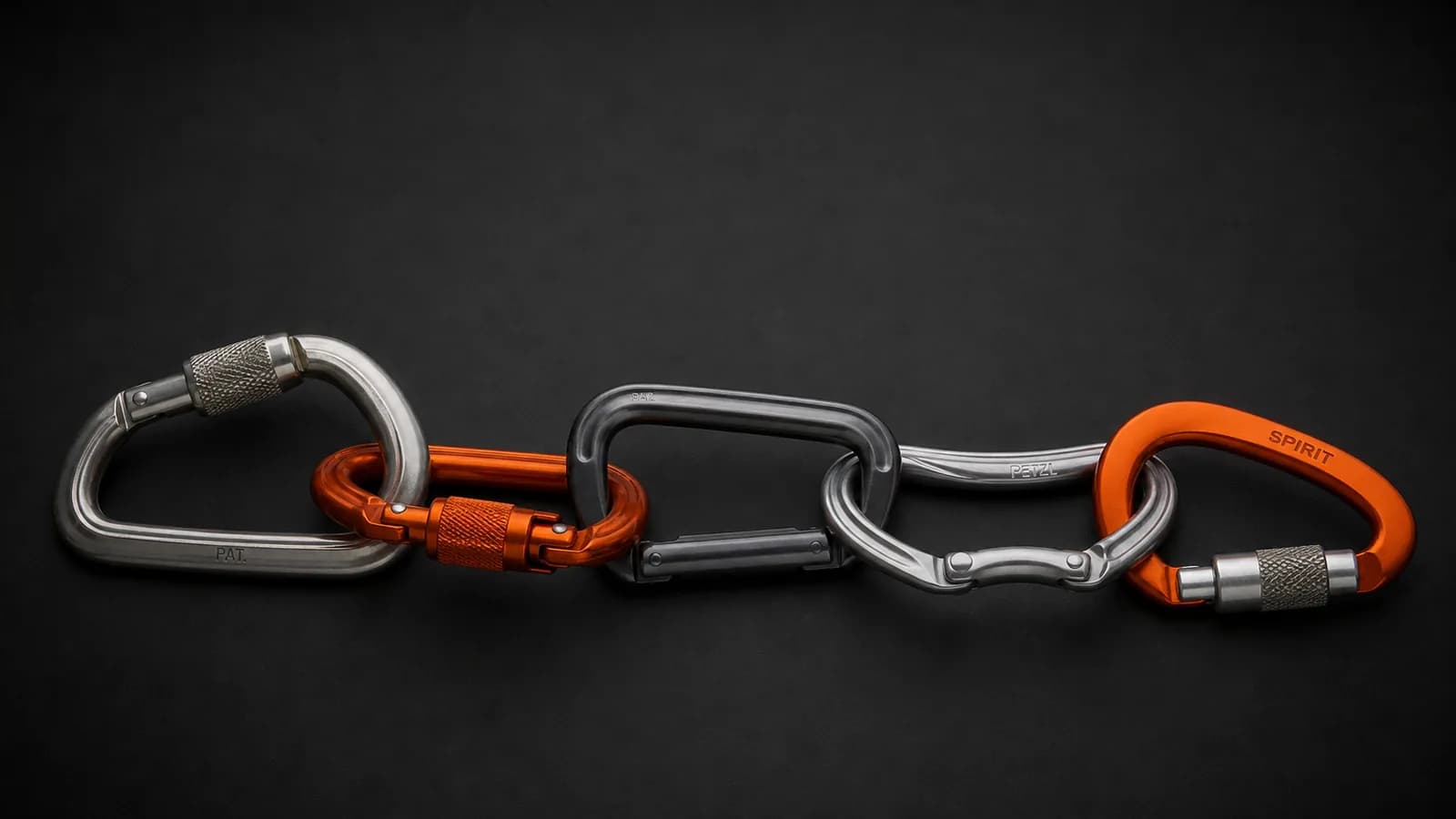 Sélection de mousquetons d'escalade Petzl et Black Diamond posés sur une dalle de granite